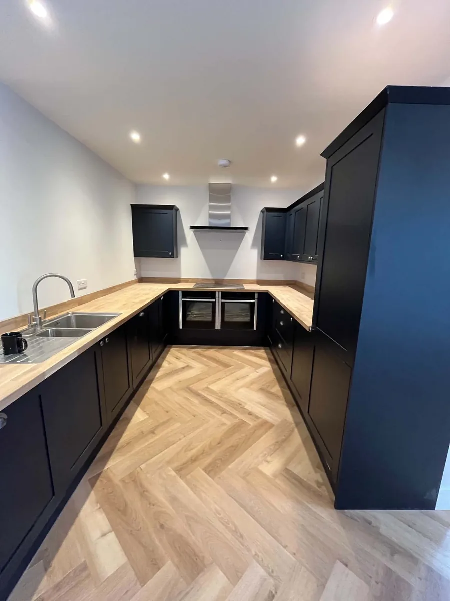 Dark fitted kitchen with solid timber worktops in a converted barn.