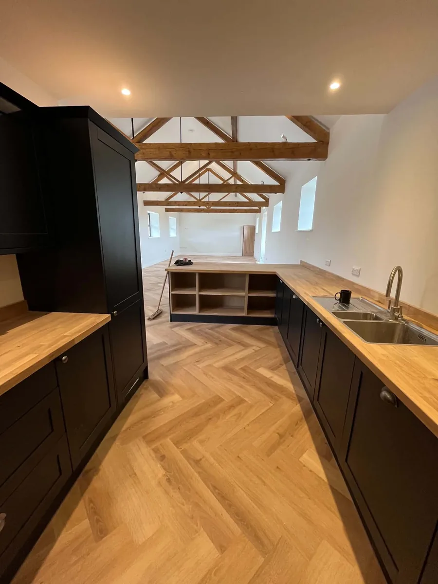 Fitted kitchen with solid wood worktops and exposed timber roof trusses.