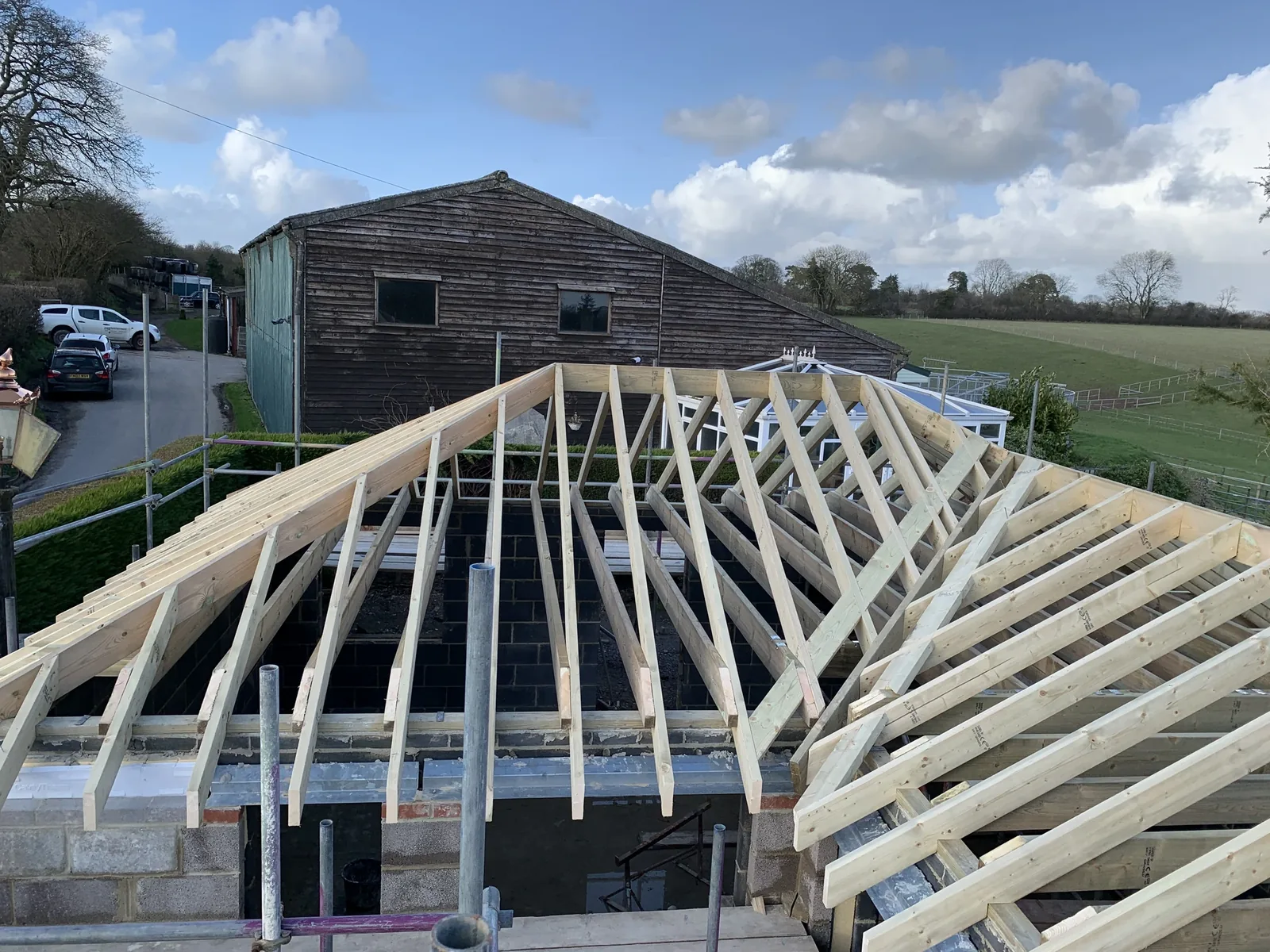 Traditional hand-cut timber roof structure under construction against a blue sky
